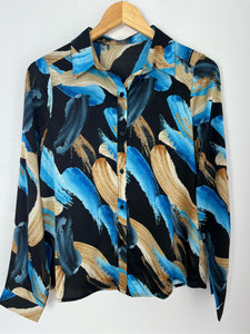 CHEMISE FLUIDE COLORÉE Chemise à motifs Manches longues Matière fluide Boutons noirs sur la longueur et aux poignets Couleurs : noir, bleu, marron et beige Composition : 100% polyester Lavage à la main obligatoire Made in R.P.C